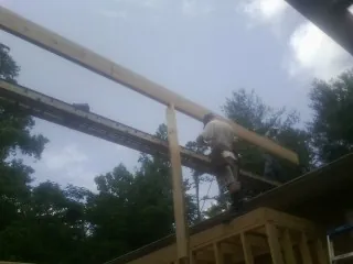Carpenter setting a ridge beam over a new addition frame — Ice Dam Removal by Roofing Brothers in Williston